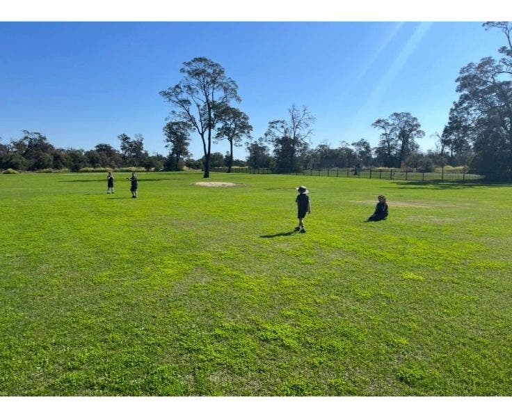 The school oval with students playing.